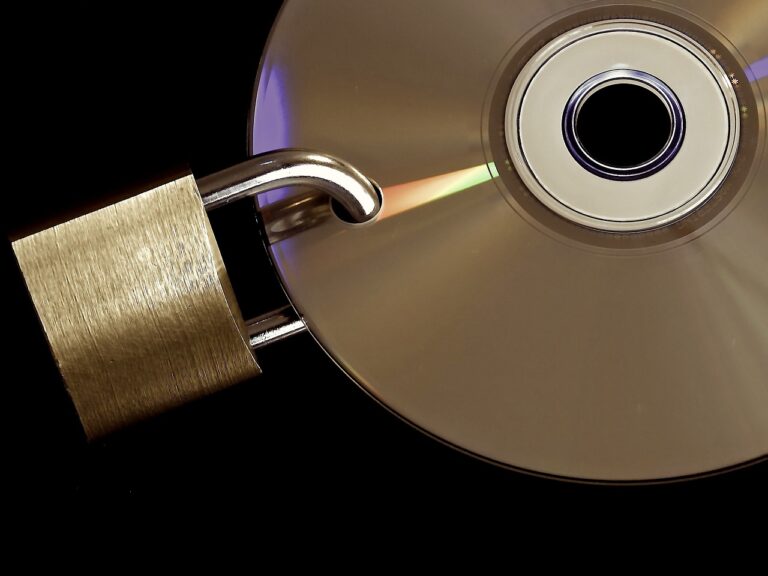 Ein glänzendes CD- oder DVD-Medium, durch das sich ein farbiges Lichtspektrum zieht, ist mit einem offenen Vorhängeschloss verknüpft, was metaphorisch für die Notwendigkeit der Datensicherung und den Schutz digitaler Informationen steht.