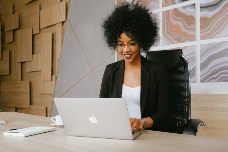 Eine lächelnde Geschäftsfrau arbeitet an ihrem Laptop, symbolisch für moderne IT-Sicherheitslösungen in einem professionellen Umfeld, wie sie von Securepoint angeboten werden.